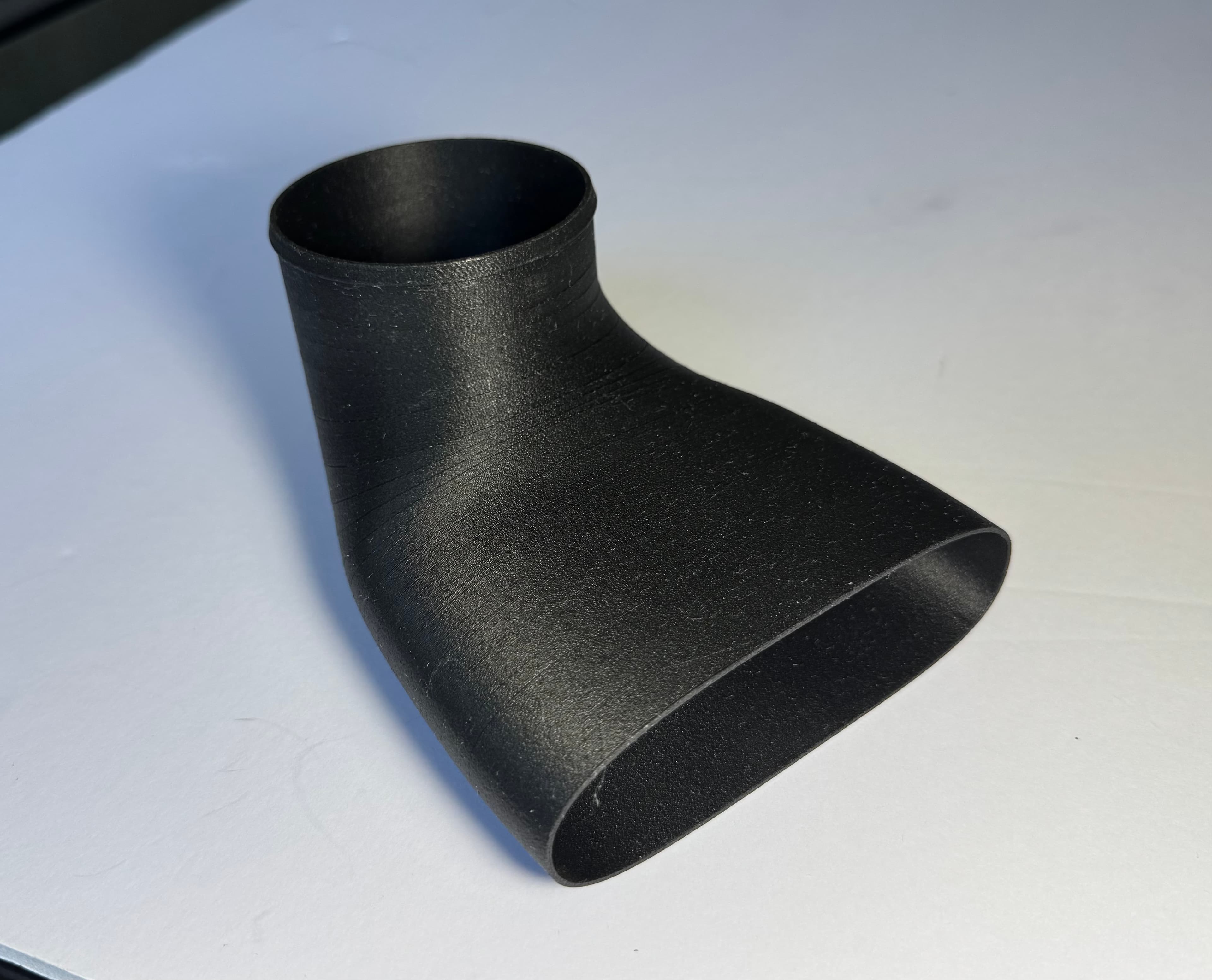 A thin-walled intake duct in nylon carbon fiber with smooth curved surfaces